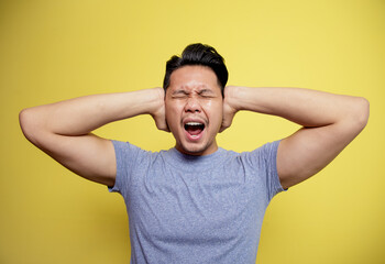 man wearing casual t-shirt dizzy expression holding head isolated on a yellow color background