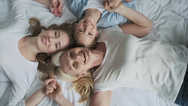 Three generations: grandma, mom and daughter - happy and smiling, lying together