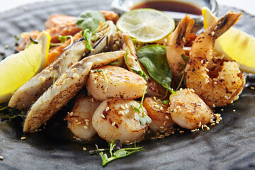 Teppanyaki Style Seafood - Grilled Mixed Seafood with Soy Sauce and Vegetables. Japanese Teppanyaki Salmon Steak, Shrimp, Scallop and Fish Fillet garnished with lemon and green salad.