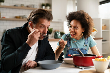 Boyfriend and girlfriend eating lunch with friends at home. Young couple enjoying the company of their friends.