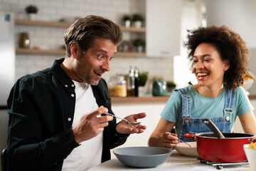 Boyfriend and girlfriend eating lunch with friends at home. Young couple enjoying the company of their friends.