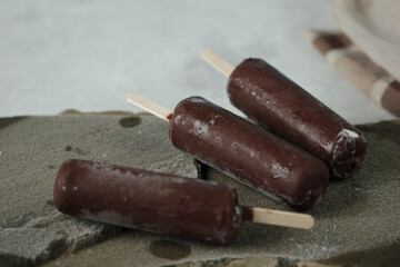 Close-up of  three chocolate iced ice creams on stick with copy space
