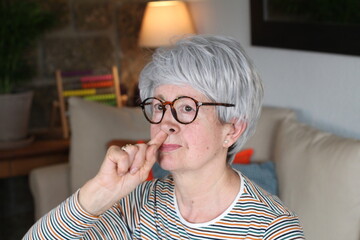 Senior woman picking nose in the sofa