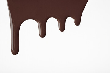 Dark chocolate liquid drops of paint flow down on isolated white background. Abstract brown color backdrop