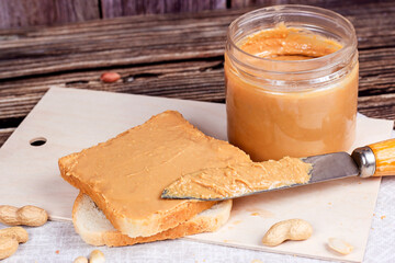 Homemade toasts  for breakfast with fresh crunchy peanut butter and nuts on light textile...