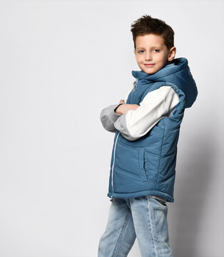 teenage boy in a blue in puffer waistcoat, sleeveless down jacket with a zipper and jeans. on white background