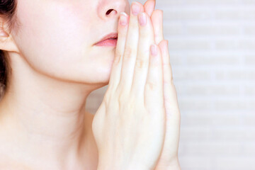 Young caucasian woman prays God and asks for help with hands near her face.