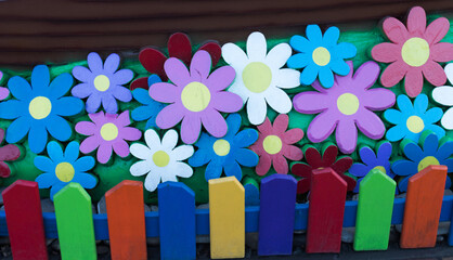 Bright colourful decorative fence of kindergarten together with the varicoloured painted flowers