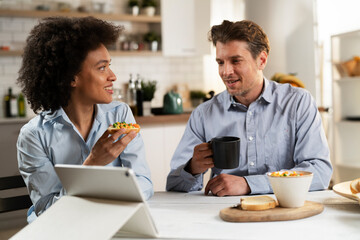 Loving couple drinking coffee and eating sandwich. Happy smiling wife enjoy in the morning with her husband.