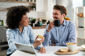 Loving couple drinking coffee and eating sandwich. Happy smiling wife enjoy in the morning with her husband.