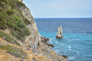 a piece of rock near the sea near the coast, a view of the coastal rocks near the castle Swallow's Nest in Crimea, a detached large piece of rock in the middle, coastline on the left, sea view