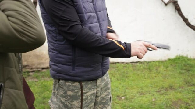 A young man talks to an instructor. Explains safety techniques and ways to fire a gun. shooting gallery. Sports shooting, hobbies, firearms dangerous weapons. outdoor activity close up