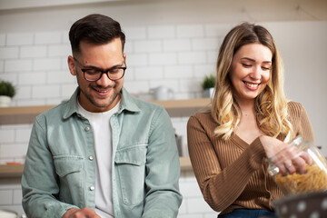 Happy smiling couple cooking together. Boyfriend and girlfriend preparing delicious food.