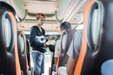 a busker using an ukulele instrument and a hat asking bus passengers for money while traveling