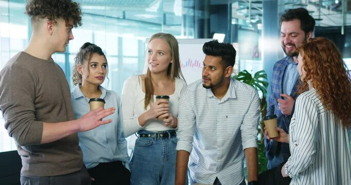 Stylish diverse business people enjoying group meeting friendly coversation during work break, laughing and sharing coffee. Multiracial students drinking coffee having fun together.