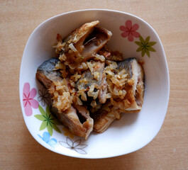 Fried fish with onions in a plate on the table