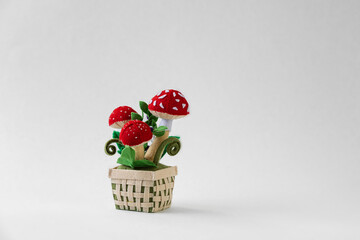 Felt little white mushrooms with a red cap, fly agaric in wicker basket on the light background.  Good luck symbol.  Hobby concept, handmade. Copy space.