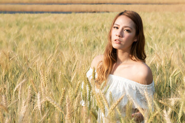 Beautiful young woman in the middle of a wheat field enjoying the rays of the summer sun