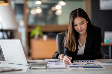 Portrait of Businesswoman working on laptop computer doing finances,accounting analysis,report,data and pointing graph at the office.