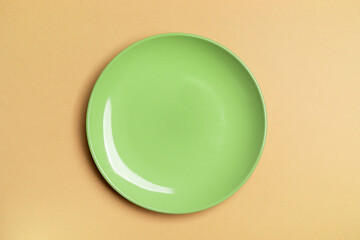 One green empty plate in center of beige background with copy space. Mock up.