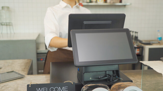 Woman barista people in apron working on POS system machine with blank empty space screen monitor on counter, cafe restaurant cashier. waitress in coffee shop. People lifestyle. Business service.
