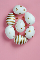 Top view on white and golden Easter eggs on pink background