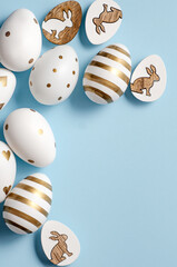 Top view on white and golden Easter eggs on blue background with free space for text or design