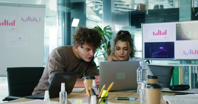 Two creative young people coworkers brainstorming ideas on new startup project. Company managers looking at computer screen discussing marketing plan.