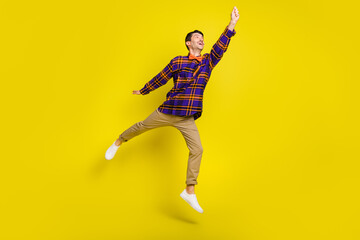 Full body photo of young handsome man happy positive smile excited jump try to catch umbrella isolated over yellow color background