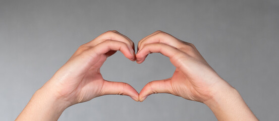 Obraz premium Hand and fingers shapes a heart. Valentine and romantic gesture.