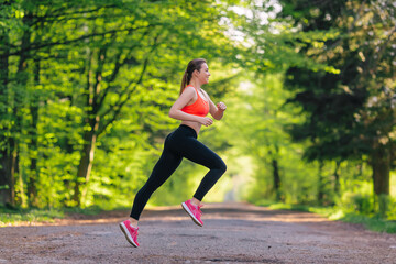 Plakat Athletic fit runner woman running in the park with trees in the