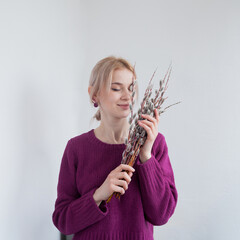 Portrait of a beautiful girl on a white background. Woman with closed eyes holds a pussy willow bouquet.