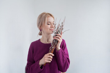 Portrait of a beautiful girl on a white background. Woman with closed eyes holds a pussy willow bouquet.