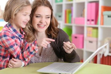 happy mother and daughter using laptop together
