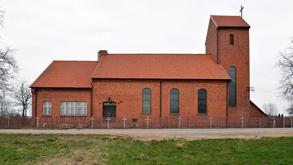 Fototapeta na wymiar Built in the neo-Gothic style of red ceramic brick in 1921, the Catholic Church of St. Andrew the Apostle in the village of Prawdziska in Masuria, Poland. The photos show a general view of the temple.