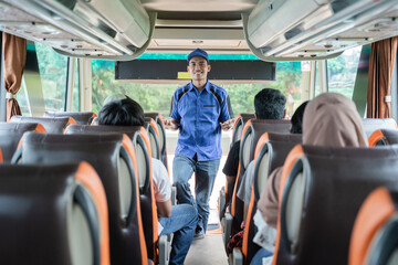 A bus crew in uniform and a hat briefs the passengers on the bus before leaving