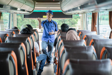 A bus crew in uniform and a hat briefs the passengers on the bus before leaving © Odua Images