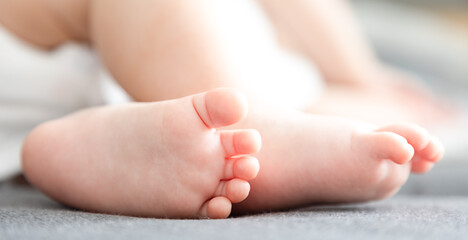 infant baby legs and feet on the grey background close-up view