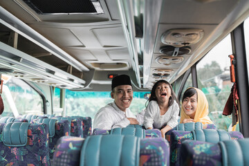 happy beautiful asian muslim holiday trip riding a bus together with family during eid mubarak...