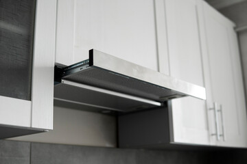 Fototapeta na wymiar Grey stainless cooking glass hood on modern white minimalist style kitchen. Kitchen supplies.