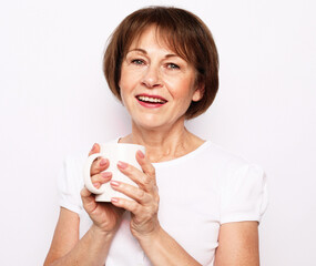 Cheerful elderly woman wear casual with cute smile holding a cup of coffee over white background.