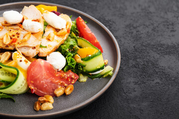 healthy salad with chicken fillet, lettuce leaves, tomatoes, cucumbers, peaches and cottage cheese on a black background, space for text