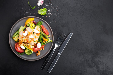 healthy salad with chicken fillet, lettuce leaves, tomatoes, cucumbers, peaches and cottage cheese on a black background, fork and knife, space for text