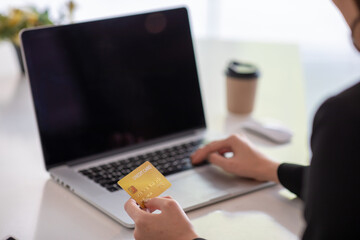 Close up woman hand using credit card and smartphone laptop for buying online shopping