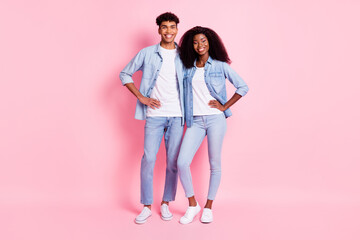 Full length photo of two positive dark skin people standing put hands on waist isolated on pink color background