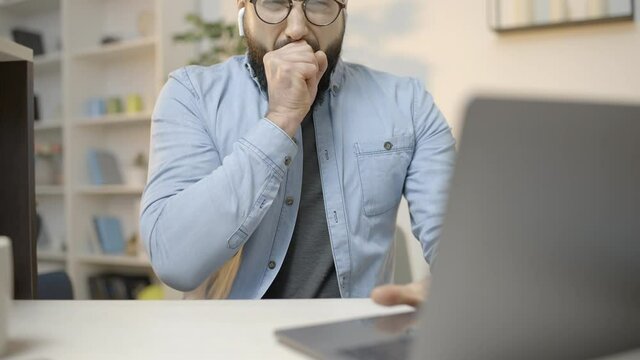 Overworked male freelancer yawning while typing on computer, burnout at work