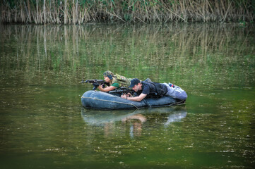 Soldier training. Special forces in camouflage uniforms paddling military rubber boat. Boat moving across the river, diversionary mission
