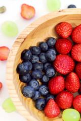 wooden plate with strawberries and blueberries close-up
