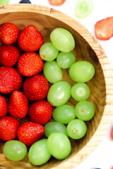 wooden plate with strawberries and white grapes close-up