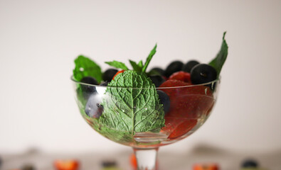 summer fruit cocktail with mint leaves close-up in a glass vase